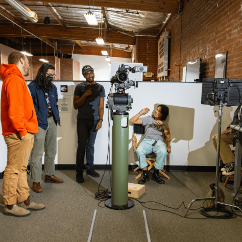 People looking at a man sitting in a chair.