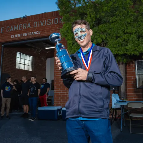 Man in blue holding a trophy. 