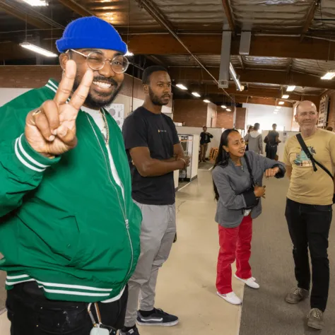 Man in green jacket giving peace sign. 