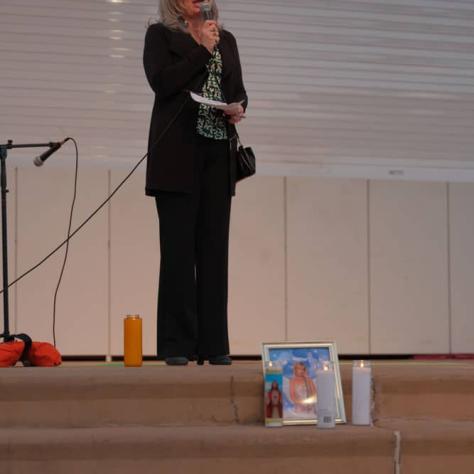 Woman on stage speaking into mic. 