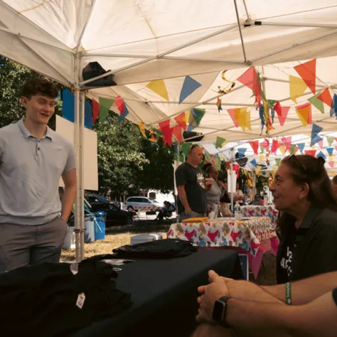 Man standing at table talking to people. 