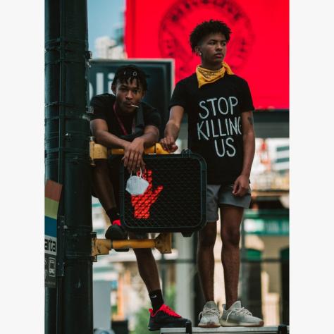 Boy standing with shirt that says "Stop Killing Us".