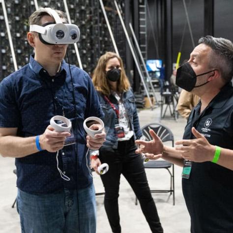 Man wearing VR set and man talking with mask. 