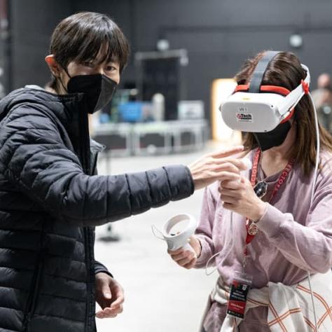 Man talking to woman wearing VR set. 