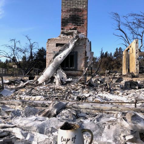 Burned down house with chimney standing and coffee cup. 