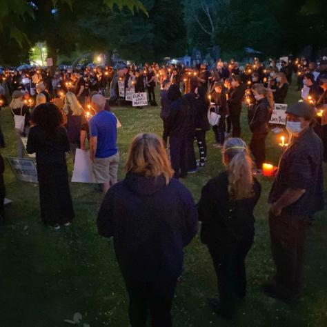 People outside at a vigil with candles. 