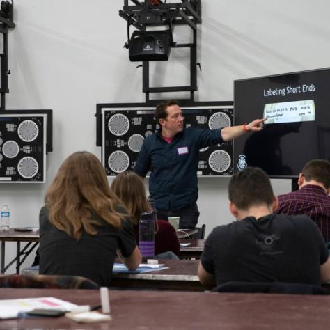 A man points to something on a screen in front of seated students