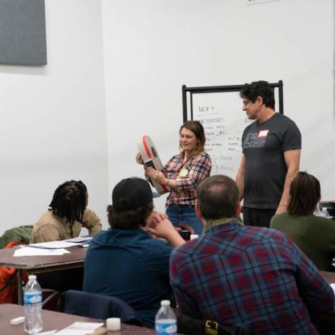 A woman shows film coming out of a film loader while people watch