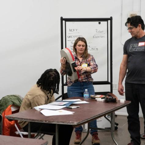 A woman shows film coming out of a film loader while people watch