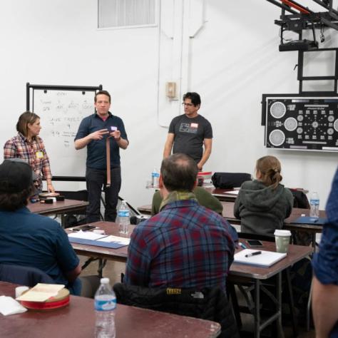 A man gives a presentation holding film while students watch