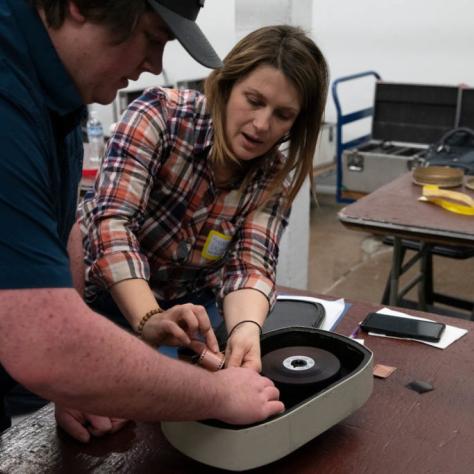 A woman shows a man how to load the film into a film loader