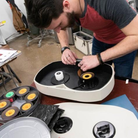 A man works on a film loader