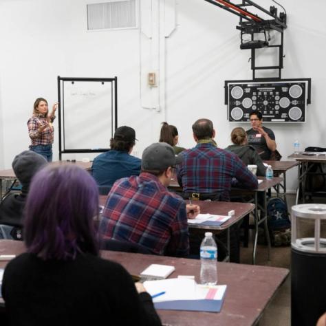 Woman presents from a large notepad in front of students